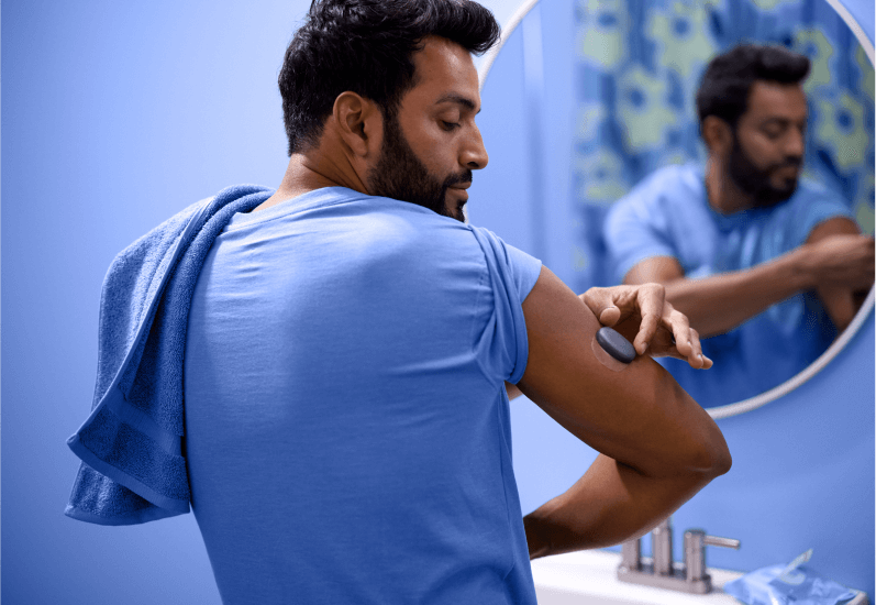 Eversense user easily applies removable CGM device in front of a mirror.